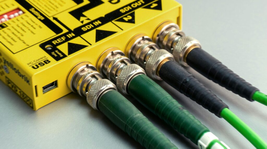 Vibrant close-up of green SDI cables connected to yellow device with visible USB port.